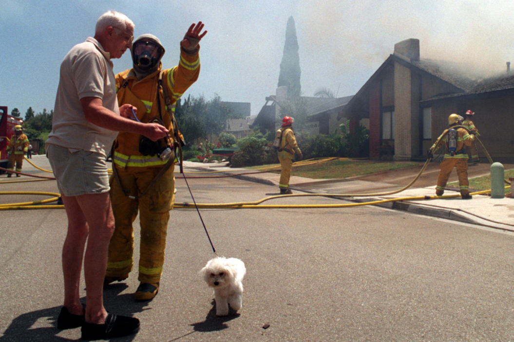 ncerned next door neighbor Dan Murray, left with his dog, talks with a Costa Mesa firefighter